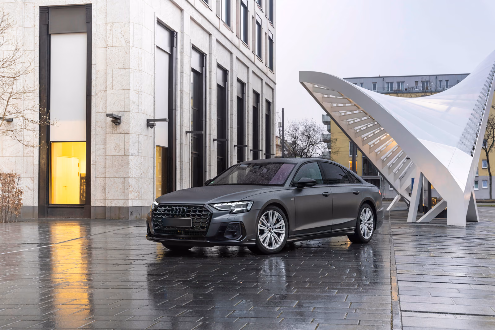 Audi A8 — спереди в три четверти на мокрой площади