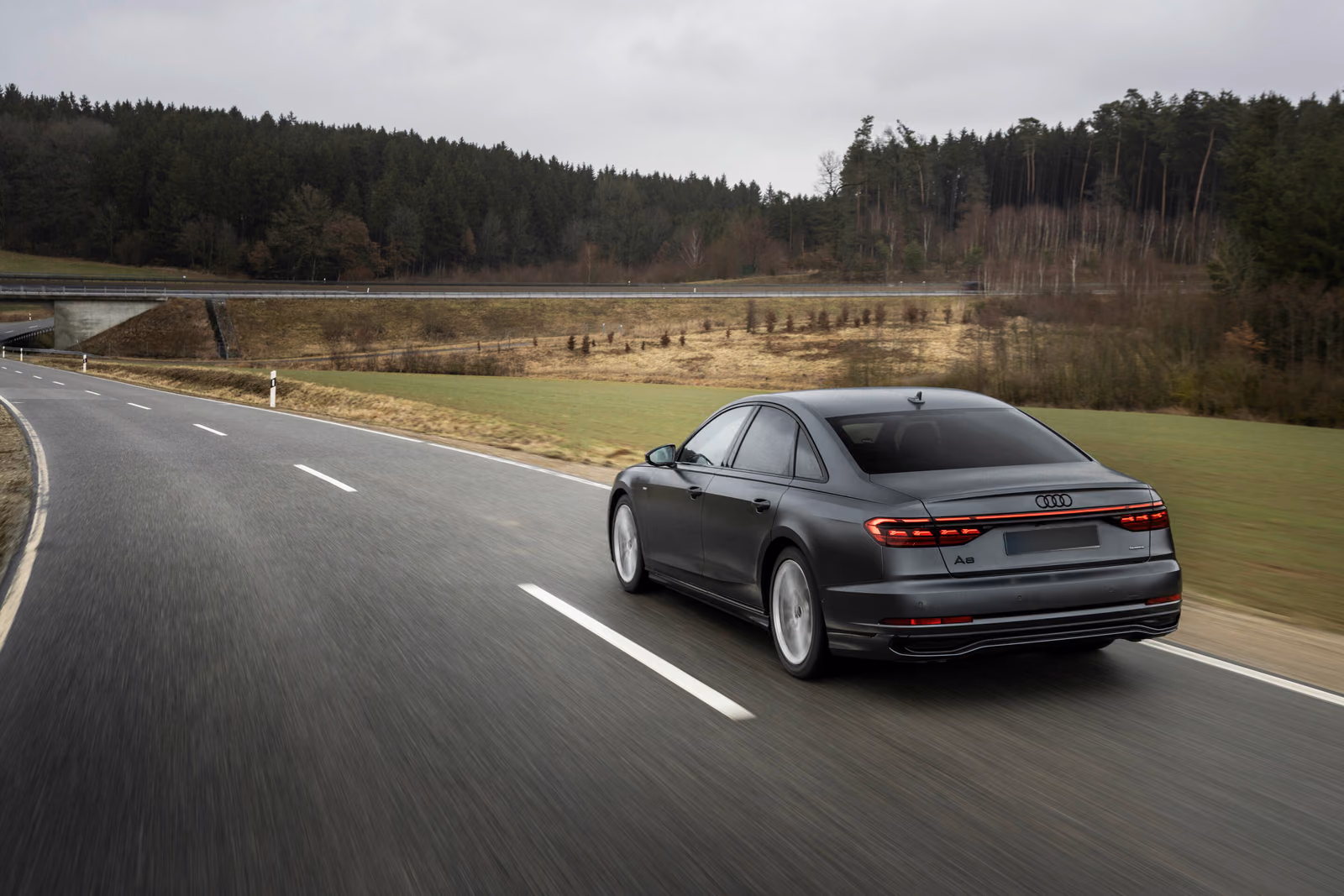 Audi A8 — в движении по холмистой дороге, вид сзади