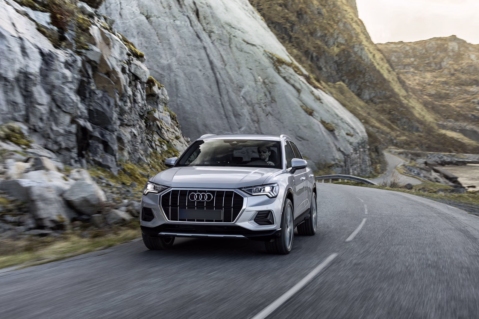 Audi Q3 — серебристый кроссовер в движении по горному серпантину