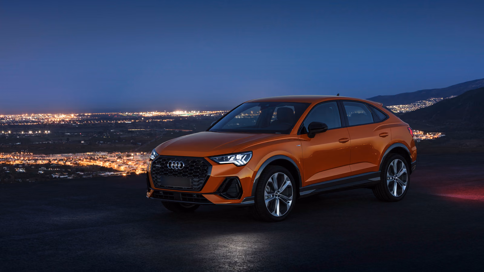 Audi Q3 — оранжевый кроссовер над ночным городом