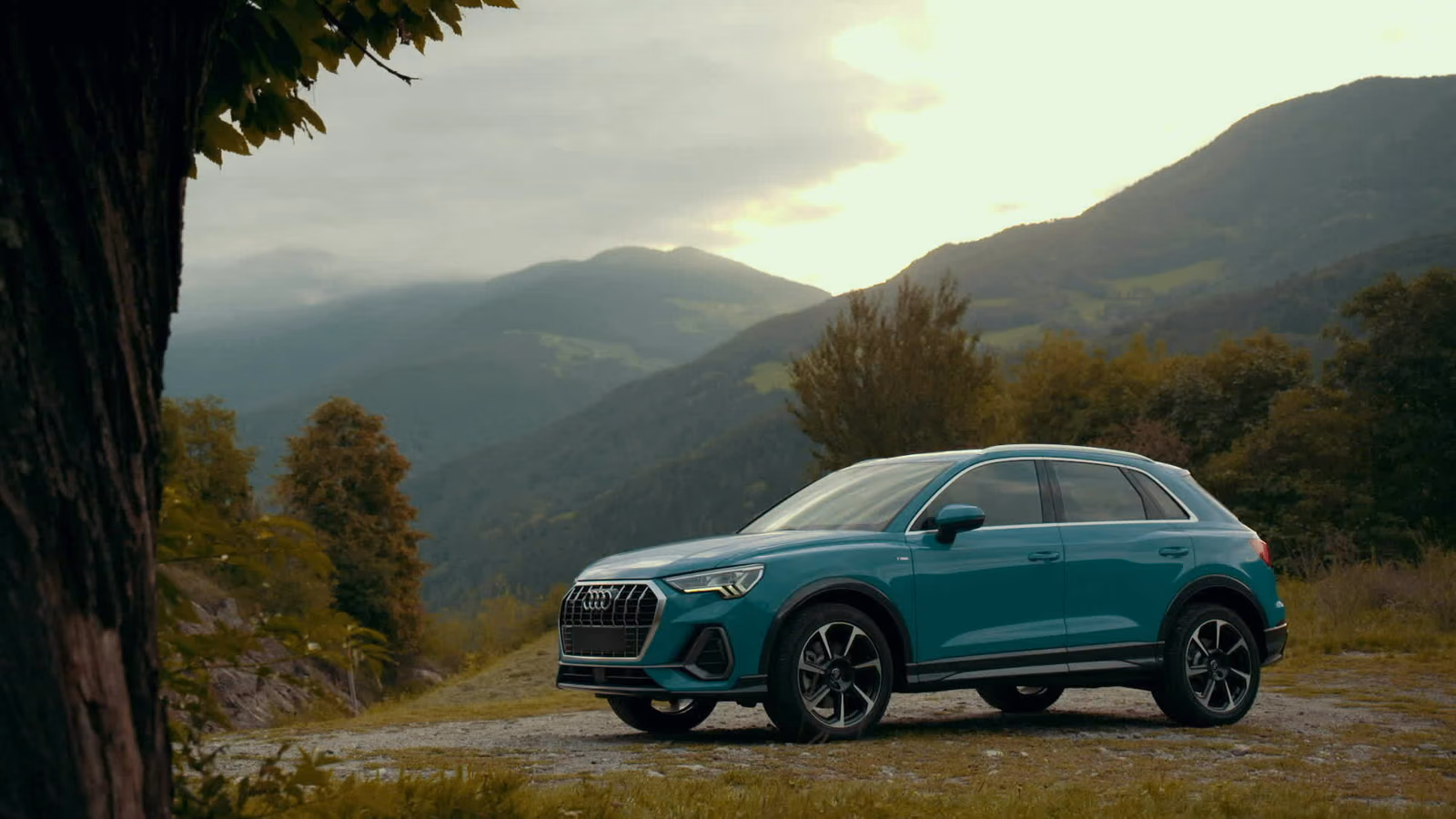 Audi Q3 — бирюзовый кузов на фоне гор в сумерках