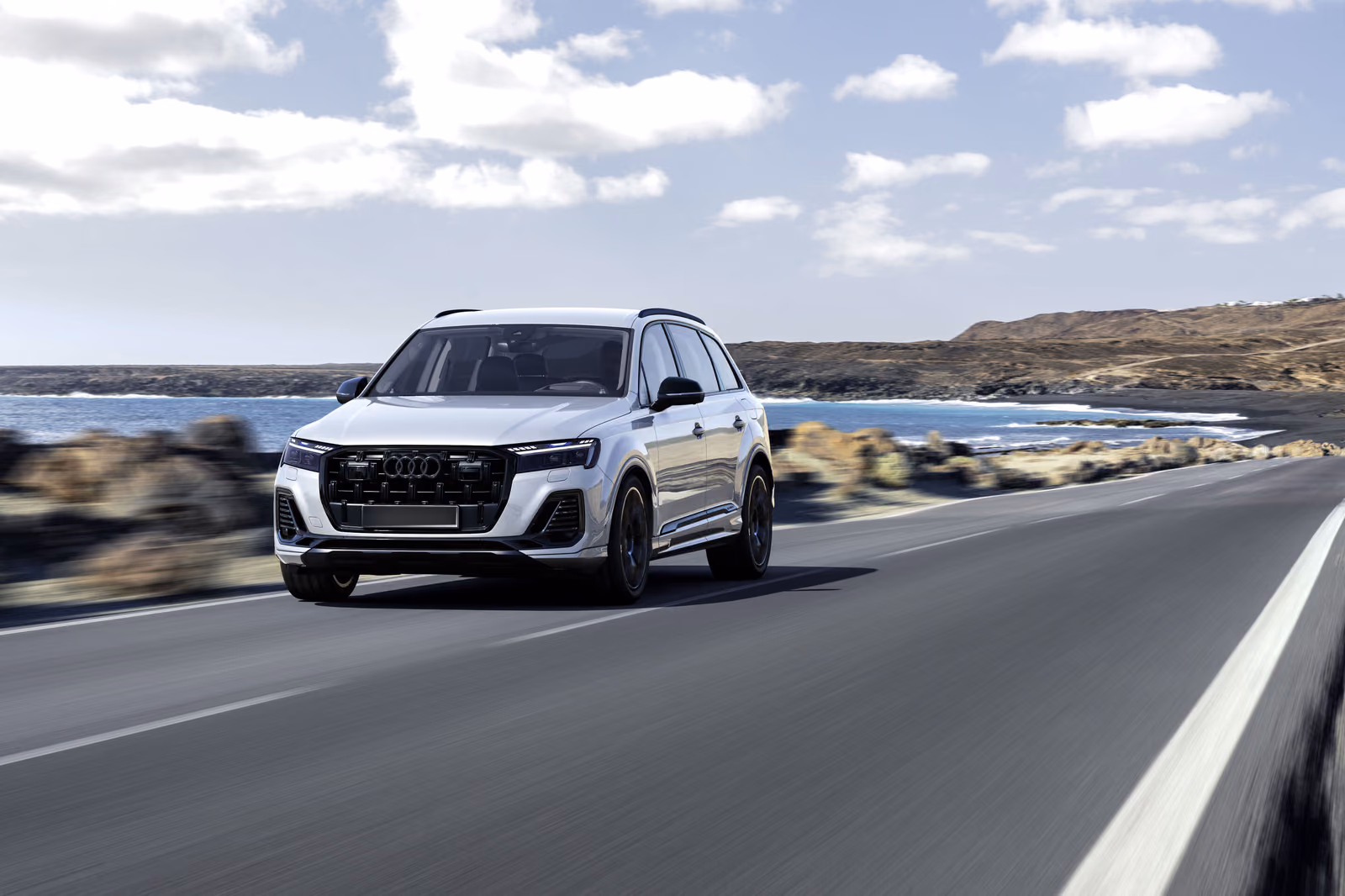 Audi Q7 — белый кузов в движении по прибрежной трассе