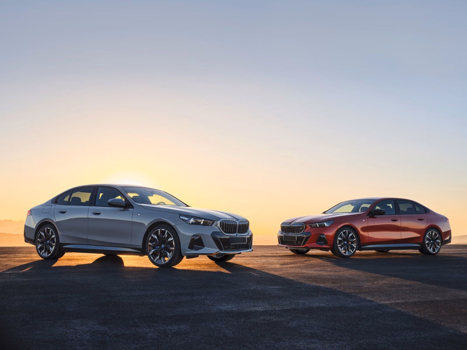 BMW 5 Series — серебристый и красный седаны на закате