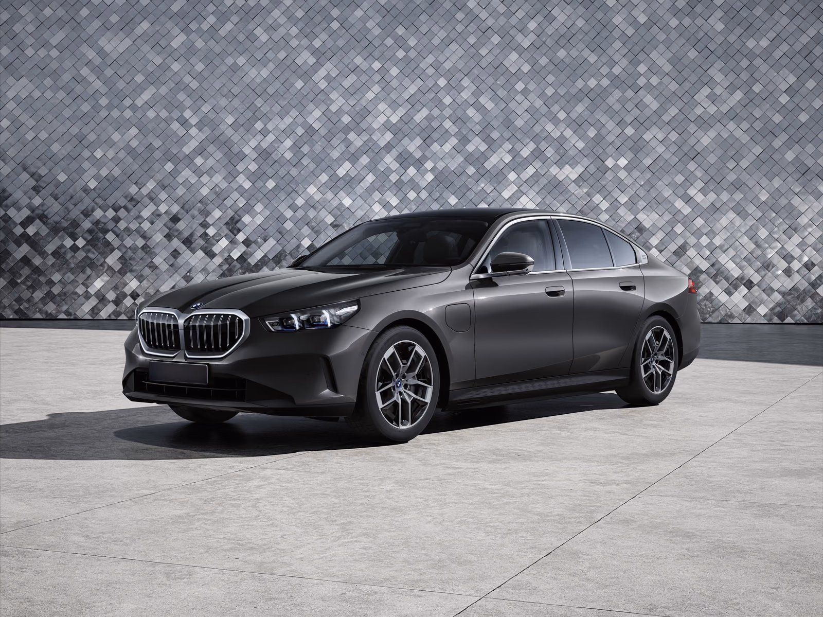 BMW 530e — тёмный седан спереди в три четверти у фасада