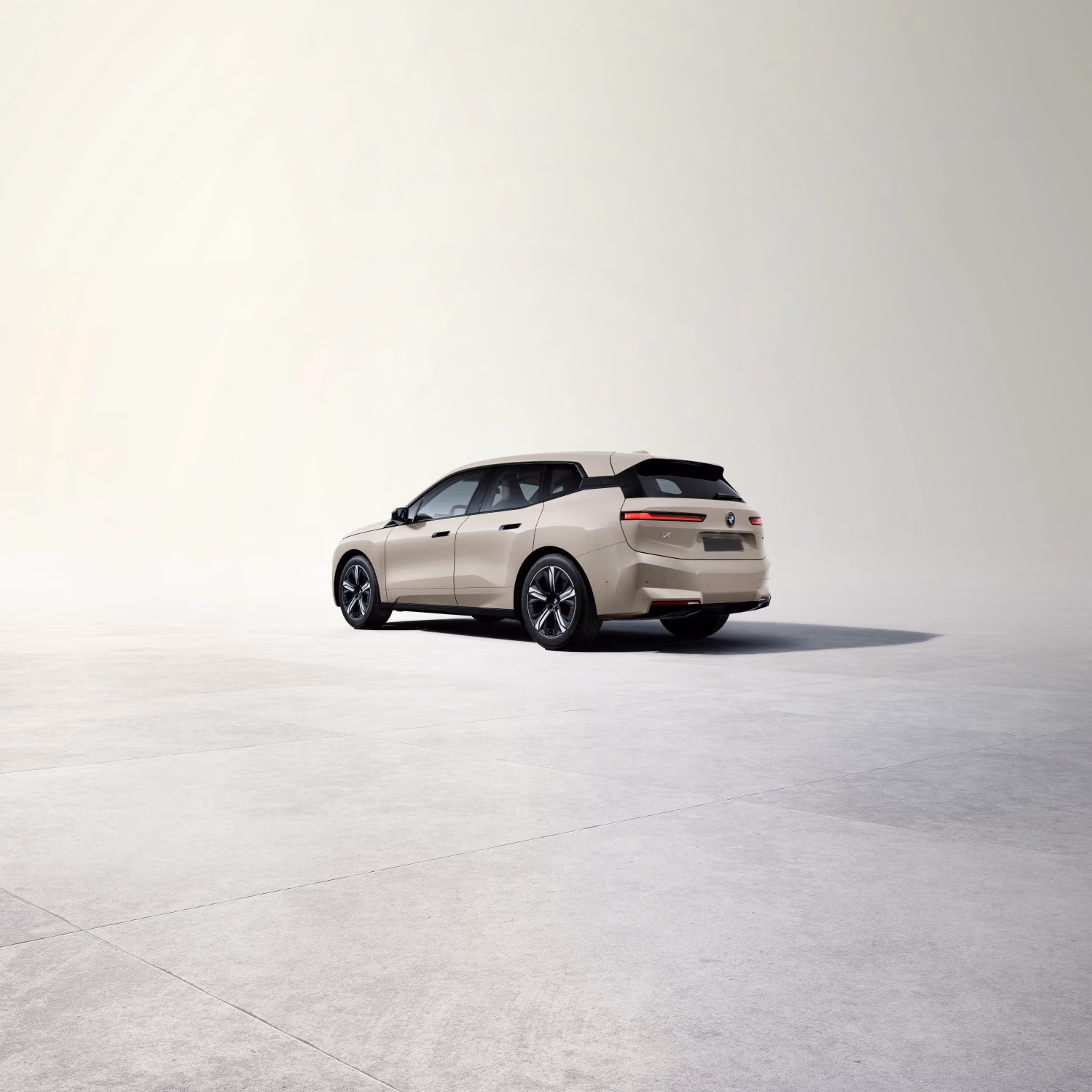 BMW iX xDrive45 — Dune Grey сзади в три четверти