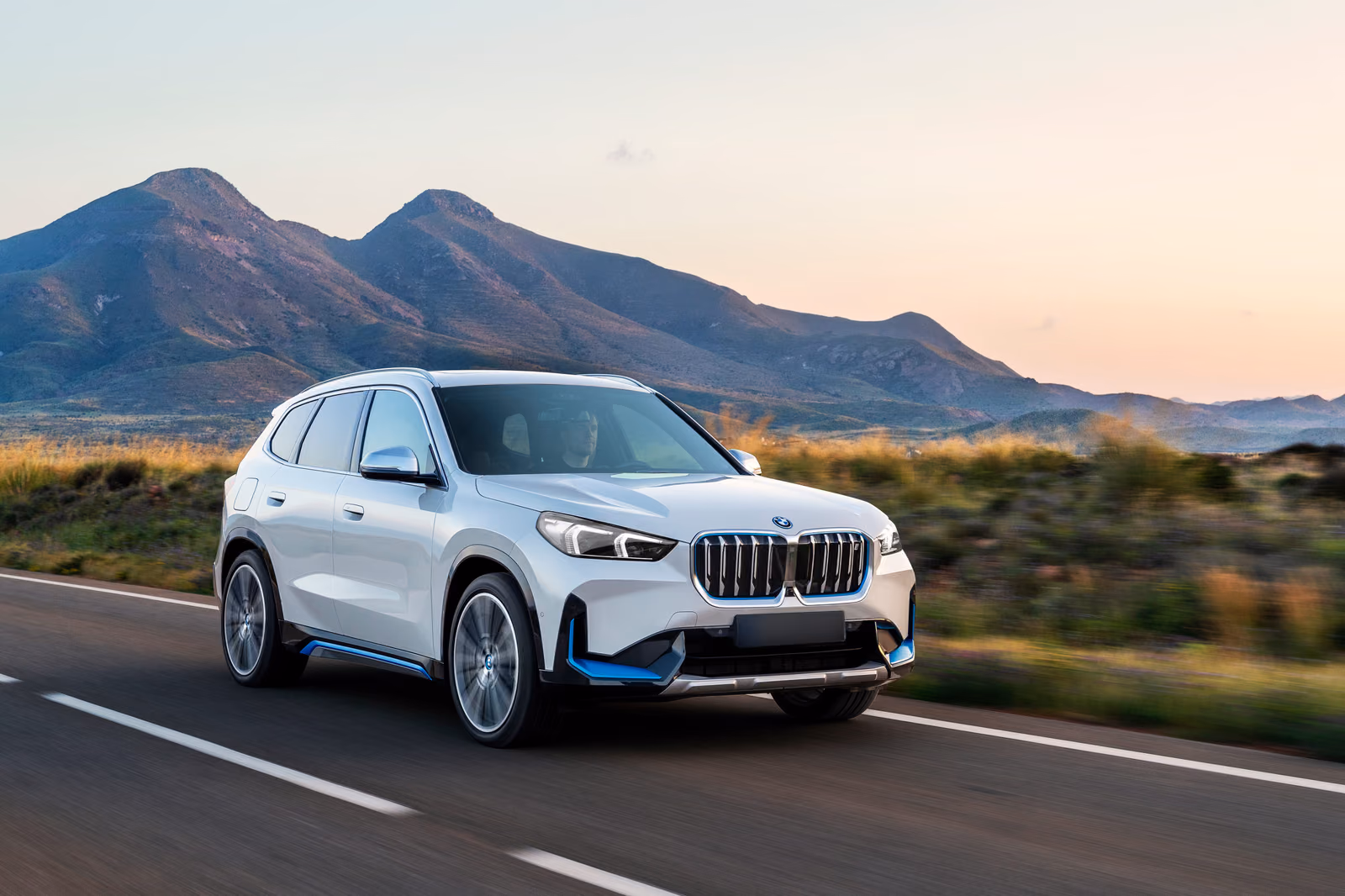 BMW iX1 на прибрежной дороге, вид спереди в три четверти