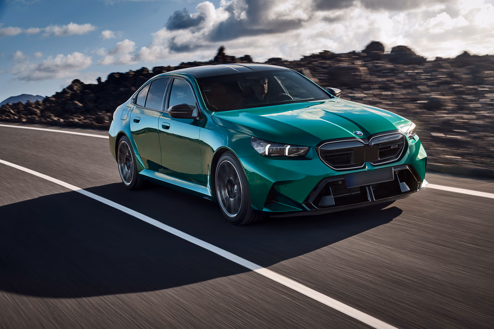 BMW M5 в движении по горной трассе, вид спереди в три четверти