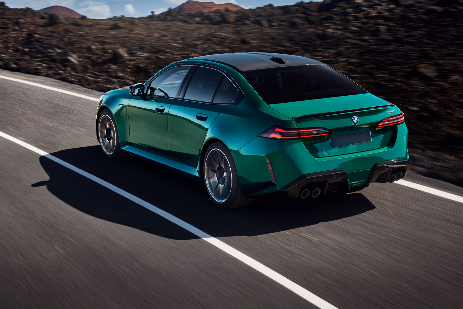 BMW M5 на ходу, вид сзади в три четверти с диффузором и четырьмя патрубками