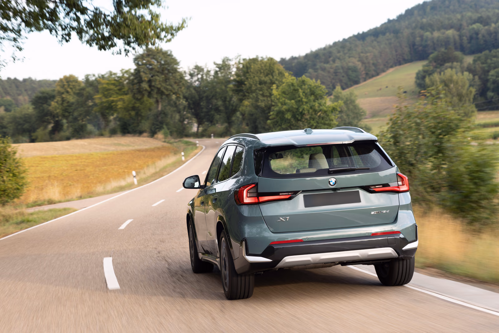 BMW X1 — вид сзади на дороге среди полей