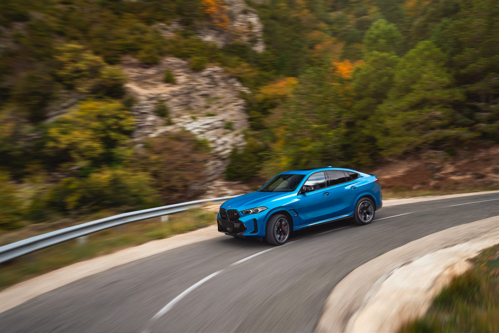 BMW X6 — на дороге среди скал, вид издалека