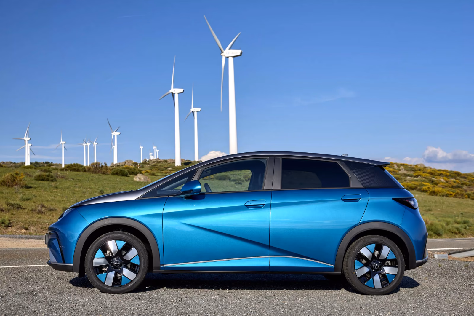 BYD Dolphin в профиль на фоне ветрогенераторов