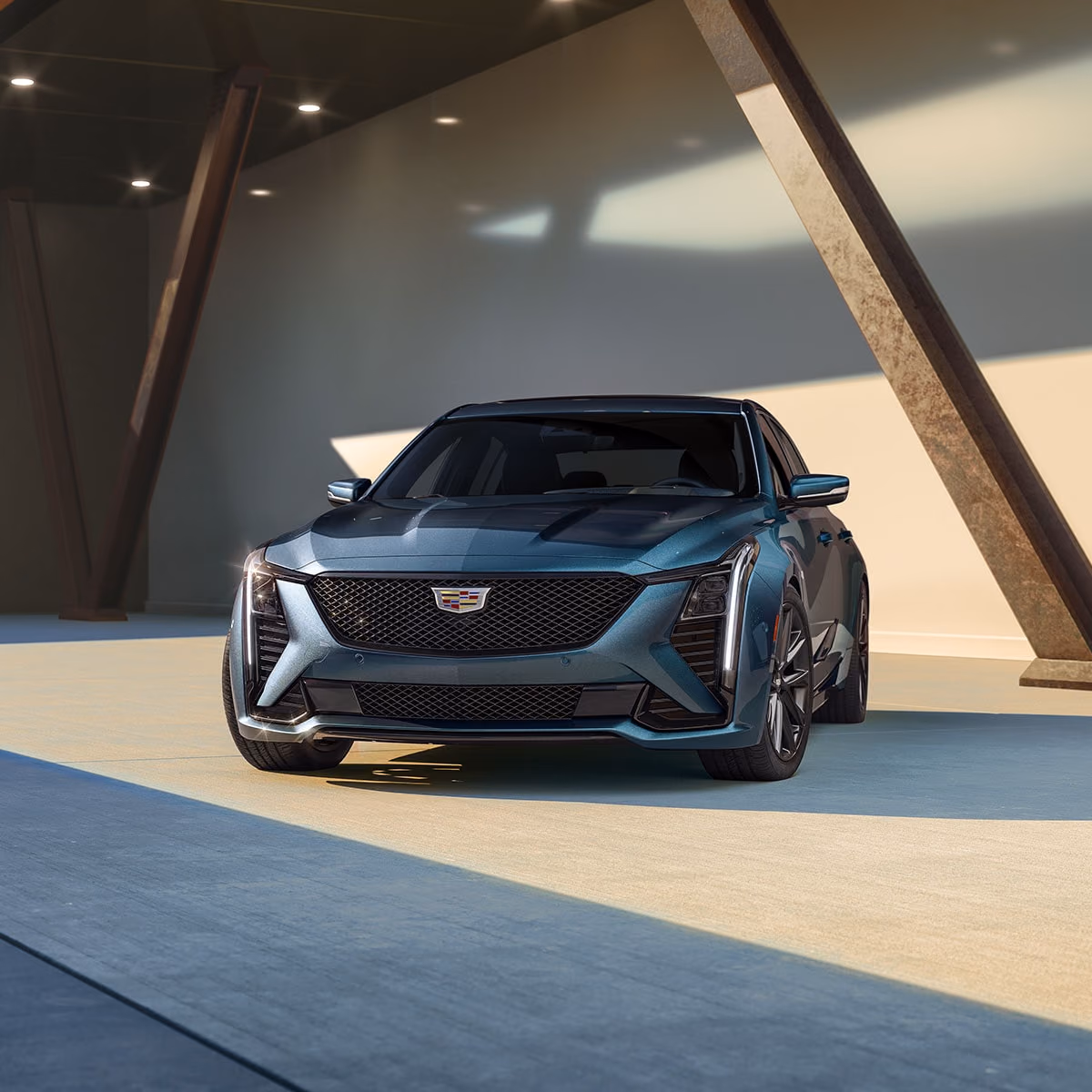 Тёмный Cadillac CT5 в переднем ракурсе у современной архитектуры