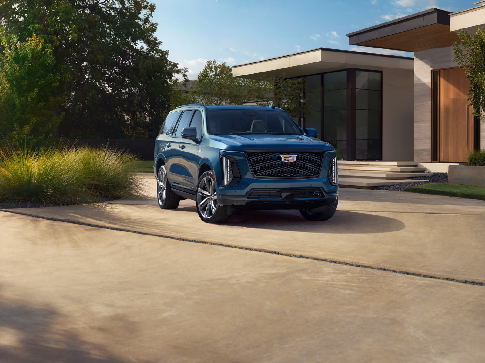 Cadillac Escalade 2025 — синий внедорожник спереди в три четверти