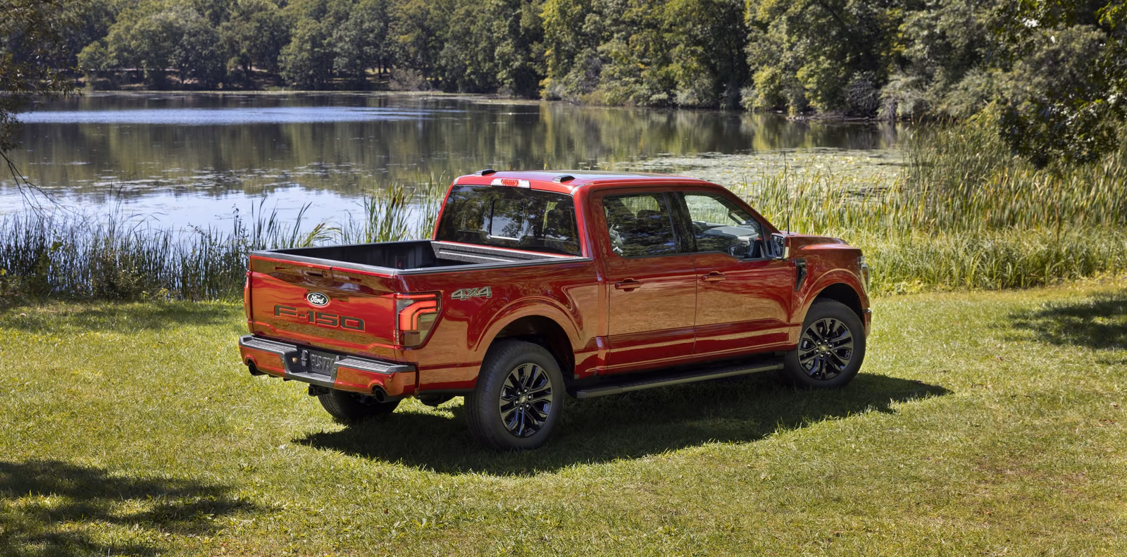 Красный Ford F-150 Lariat у озера, вид спереди в три четверти