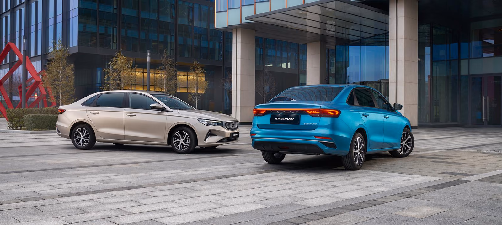 Светлая Geely Emgrand сзади у здания
