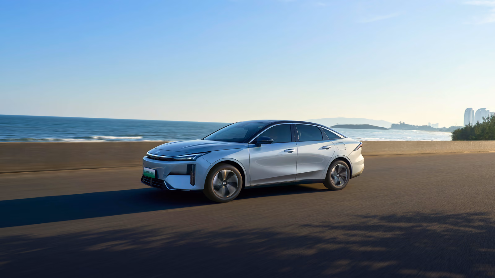 Серебристый Geely Galaxy L6 на пляже, вид спереди в три четверти