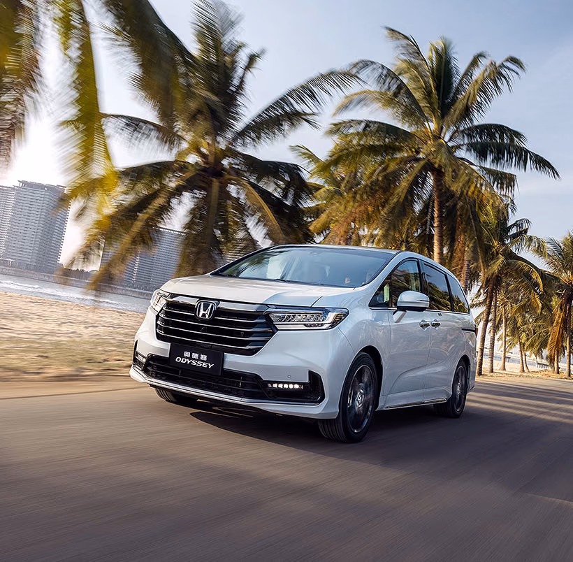 Белая Honda Odyssey e:HEV в движении у моря