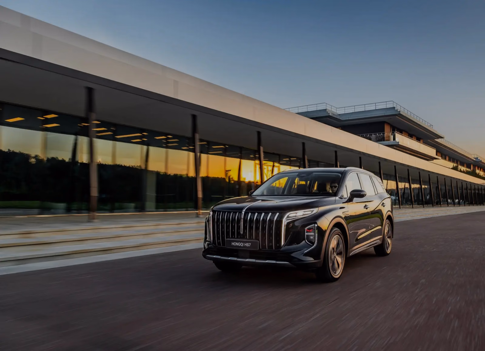 HONGQI HQ9 у стеклянного здания на закате
