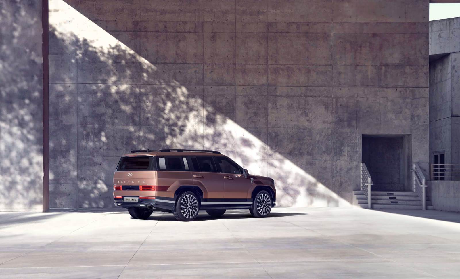 Hyundai Santa Fe — вид сзади в три четверти у бетонного здания, H-образные фонари