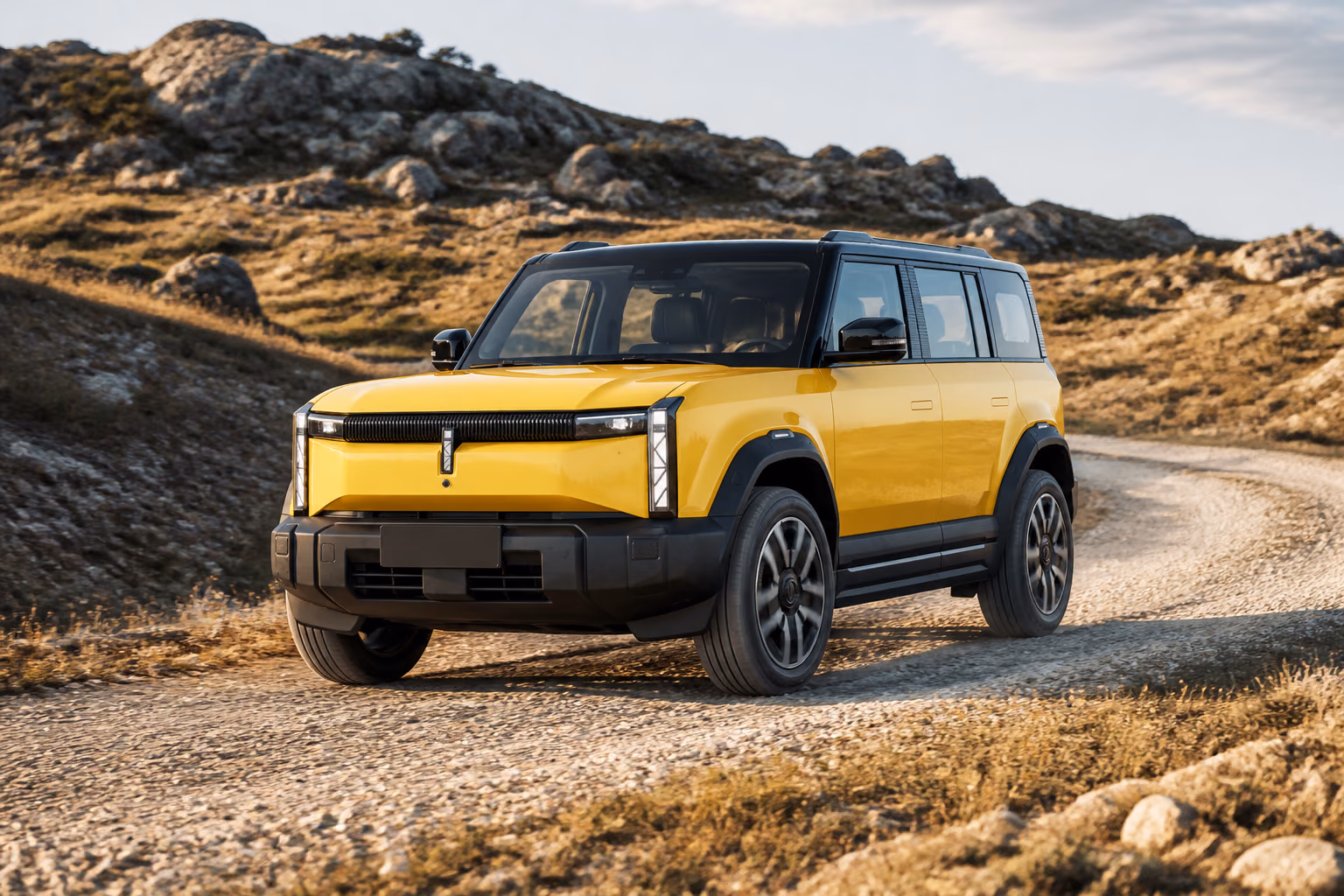 Жёлтый iCAR 03 на гравийной дороге в холмах