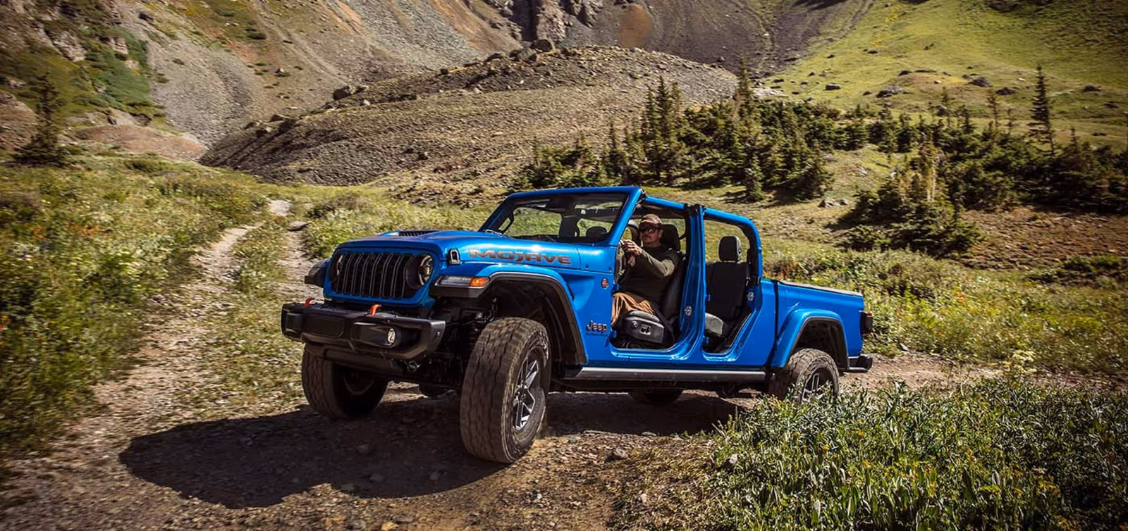 Синий Jeep Gladiator с открытым кузовом на горной дороге