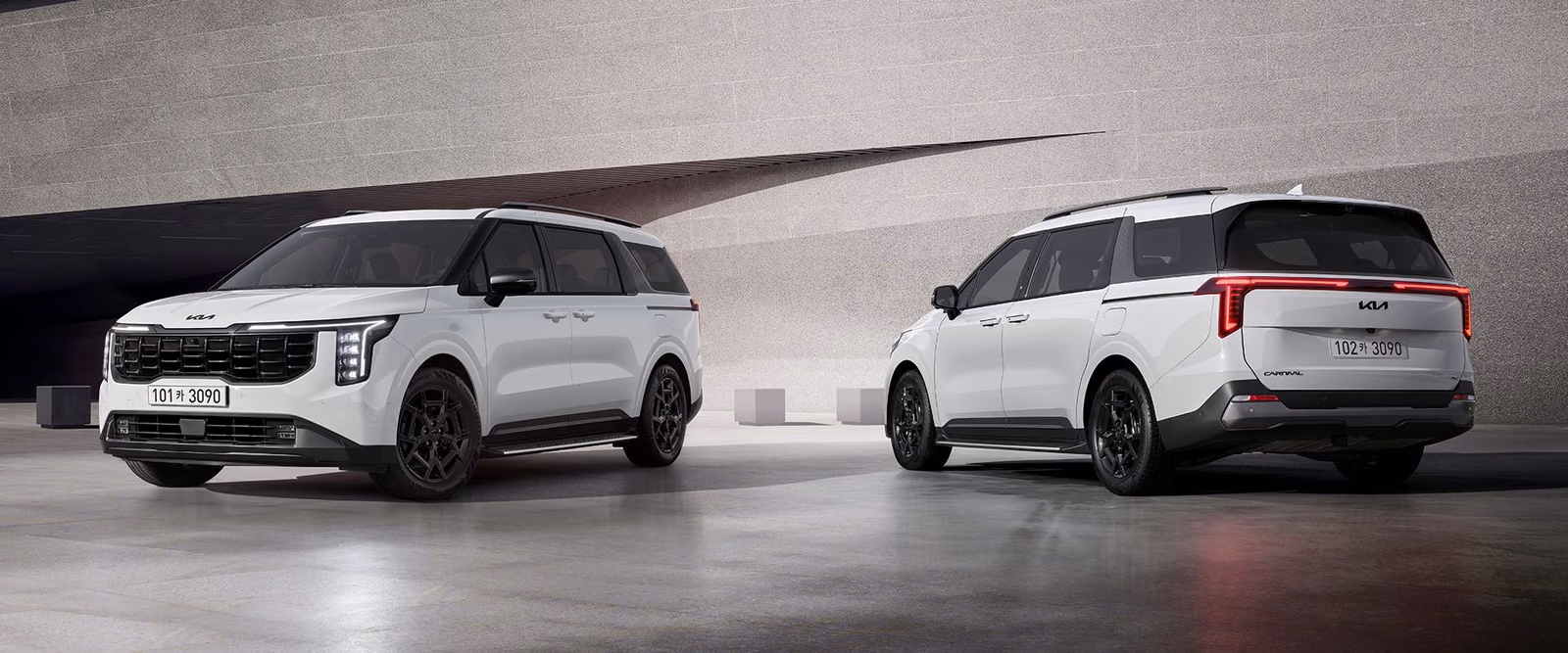 Две Kia Carnival X-Line в студии, вид спереди и сзади