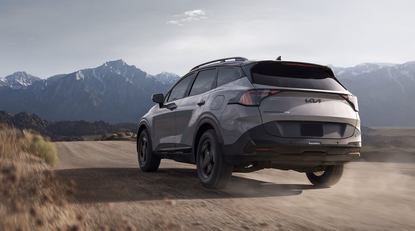 Kia Sportage на грунтовке у гор, вид сзади