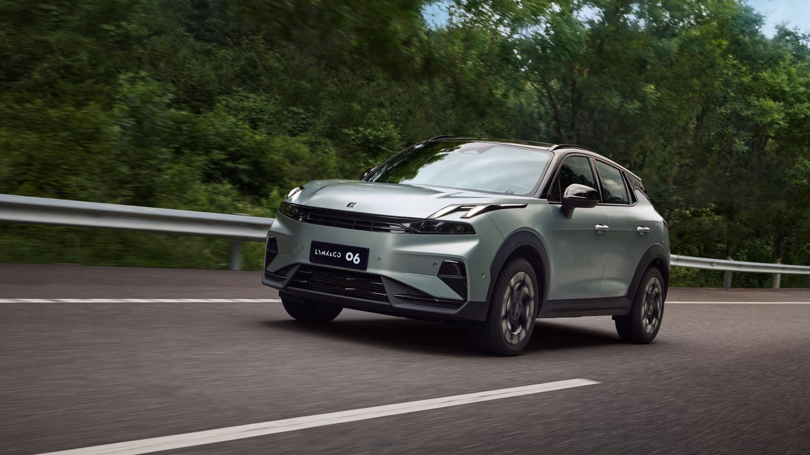 Зелёный Lynk & Co 06 в движении по загородной дороге