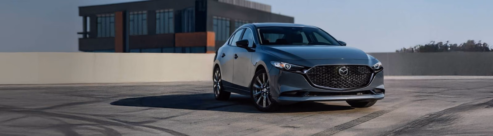 Mazda 3 синего цвета у здания