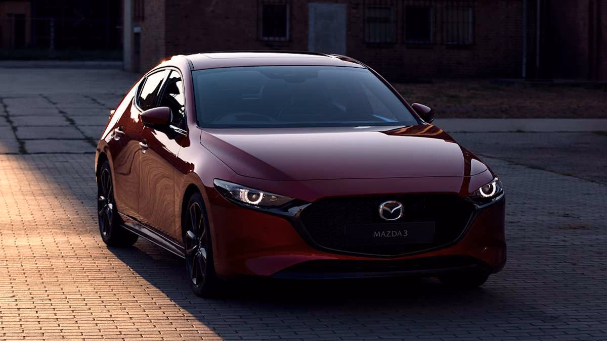 Красная Mazda 3 у городского здания