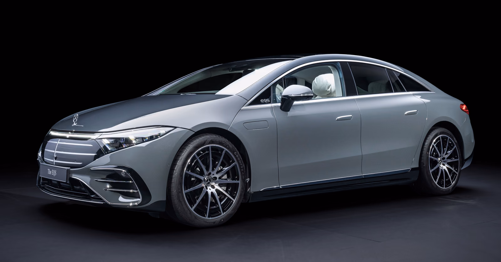 Mercedes-Benz EQS — серый лифтбек спереди в три четверти в тёмной студии
