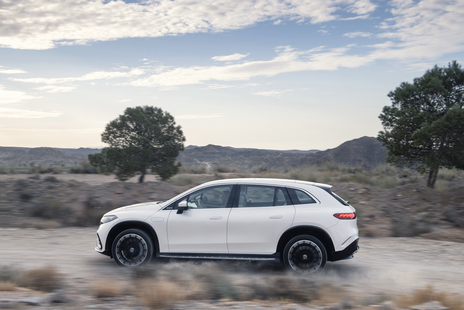 Mercedes-Benz EQS SUV — профиль на грунтовой дороге среди холмов