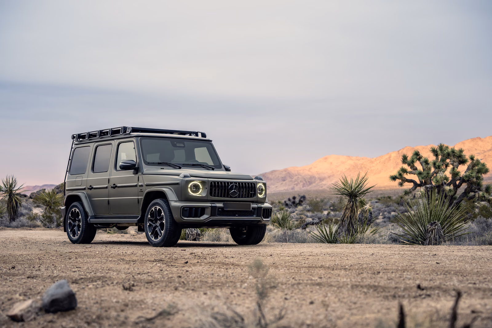 Mercedes-Benz G-Class W465 — оливковый внедорожник на закате среди пустынных скал