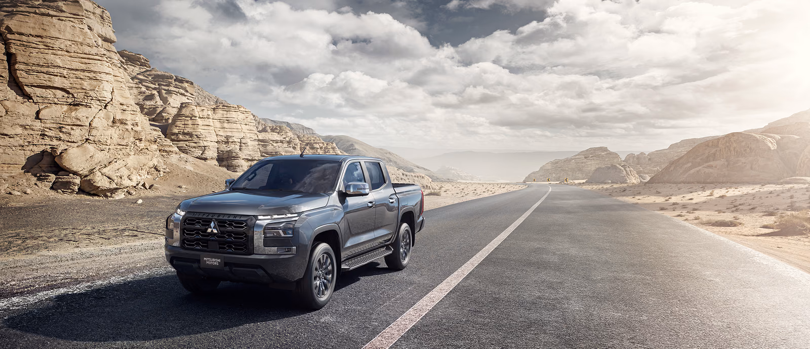 Mitsubishi L200 — серый пикап на пустынной дороге