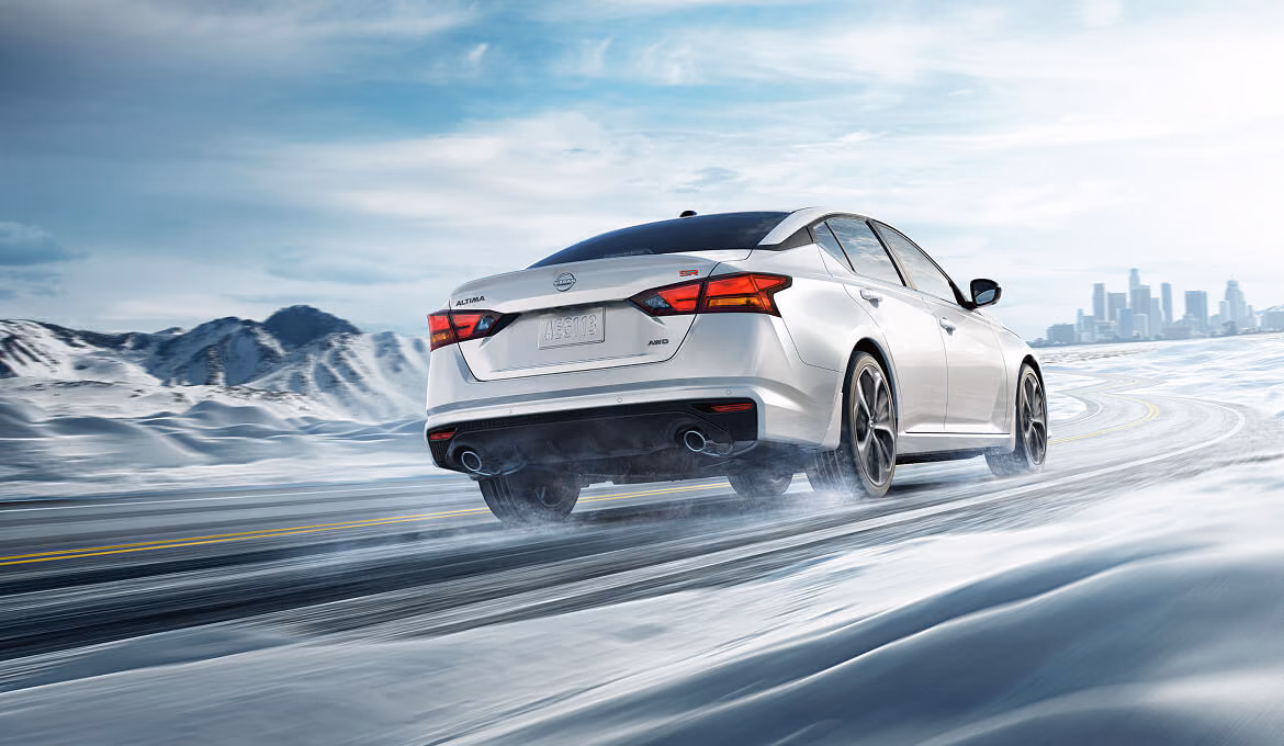 Белая Nissan Altima L34 на зимней дороге — вид сзади