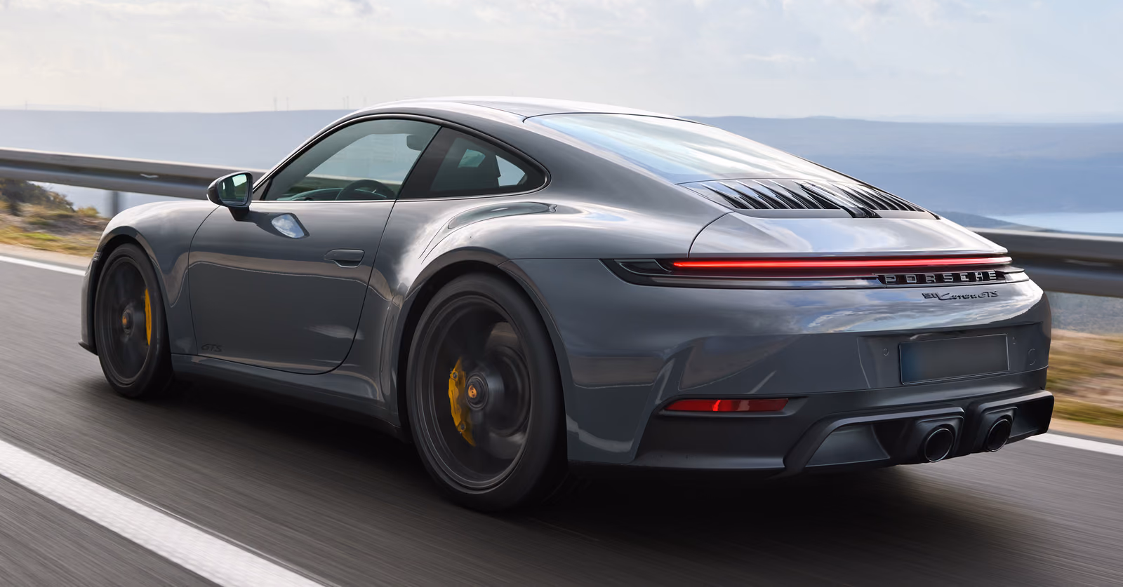Porsche 911 Carrera GTS — вид сбоку сзади на приморском шоссе