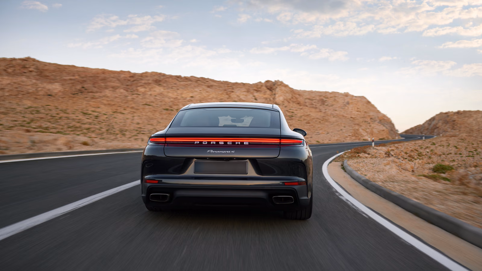 Porsche Panamera в движении, вид сзади с фонарной полосой