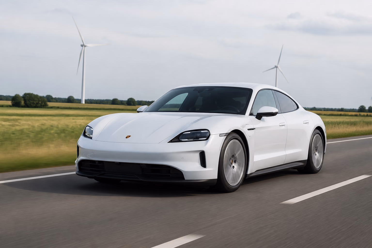 Porsche Taycan на пустой трассе рядом с ветрогенераторами