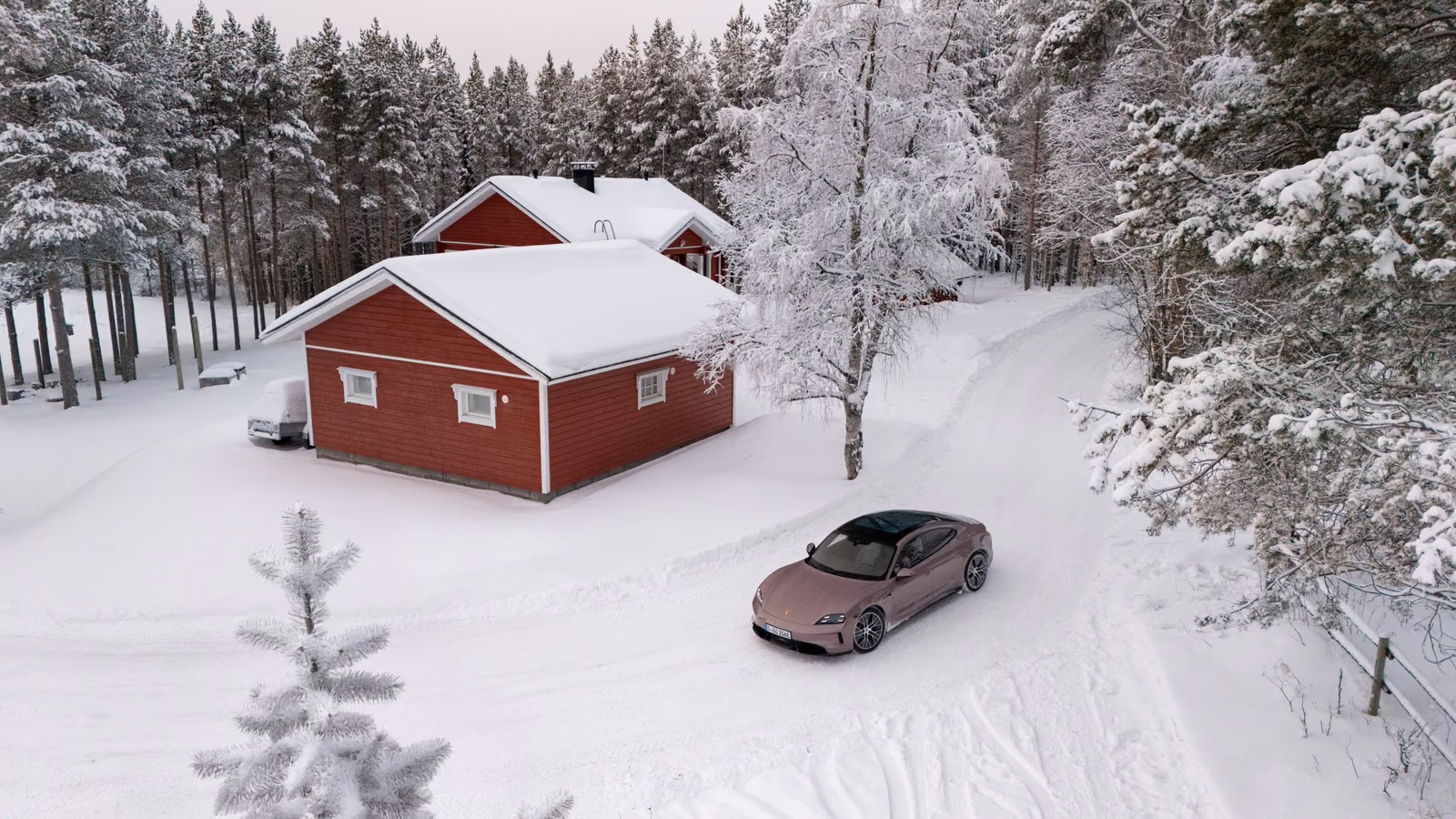 Porsche Taycan 4 на заснеженной дороге у загородного дома