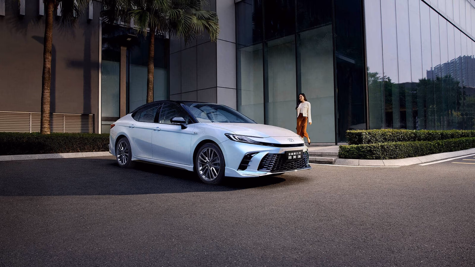 Toyota Camry в белом цвете на городской улице, вид спереди сбоку